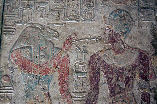 Carved and painted relief on the wall of the Temple of Beit al-Wali on the shores of Lake Nasser near Aswan, Egypt. The ram headed god Khnum is shown with an ankh pointing at the face of the Pharoah Ramses II. Khnum is thought of as the god who created life.