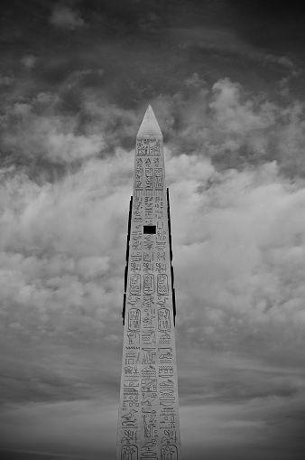 Black and white photo of The obelisk outside the Luxor Hotel in Las Vegas against sky with clouds.