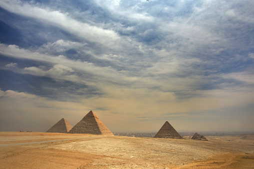 Panoramic view of the pyramids from the Giza Plateau on a sunny day in Cairo, Egypt. From left: the Pyramid of Chufu /Cheops/, Khafre /Chephren/, Menkaure /Mykerinos/ and one of the small pyramids popularly known as Queens' Pyramids. The Pyramid Fields from Giza to Dahshur is on UNESCO World Heritage List"