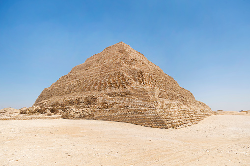 Great step pyramid of Djoser, Saqqara. Ruins in front of the pyramid, blue sky.